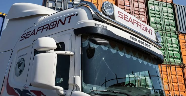 Seafront Logistics lastebil foran containere, symboliserer effektivisering med AI-løsningen SEMINE for automatisk fakturahåndtering og bedre kontroll over økonomien.